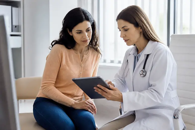 Consultation médicale pour canthopexie : patiente et chirurgien discutent d'un écran.