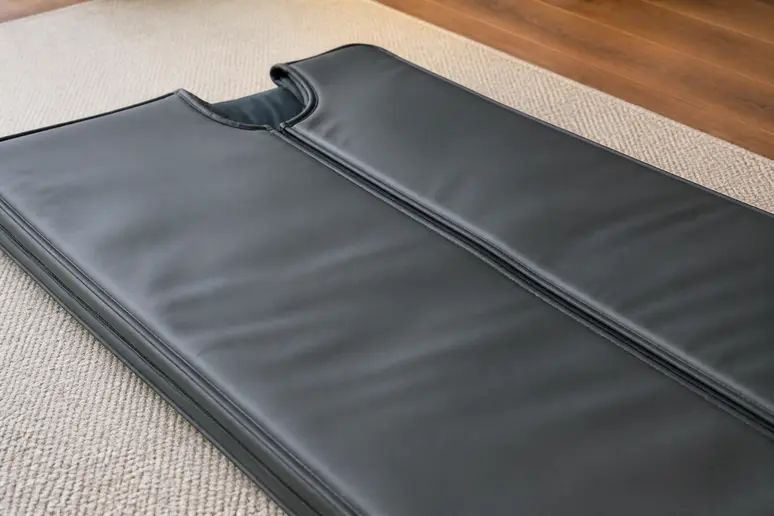 Gros plan sur une couverture sauna infrarouge neuve, posée à plat, mettant en avant la qualité des matériaux.