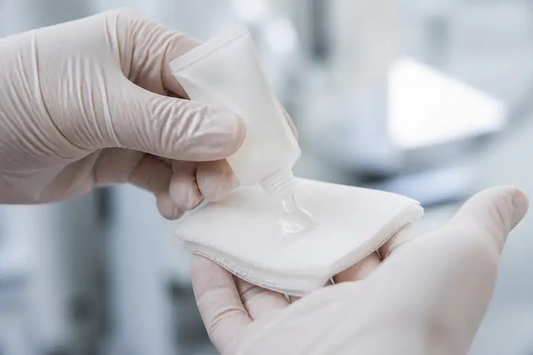 Main professionnelle appliquant un gel cicatrisant sur un pansement, photo-cicatrice-lifting-cuisse.