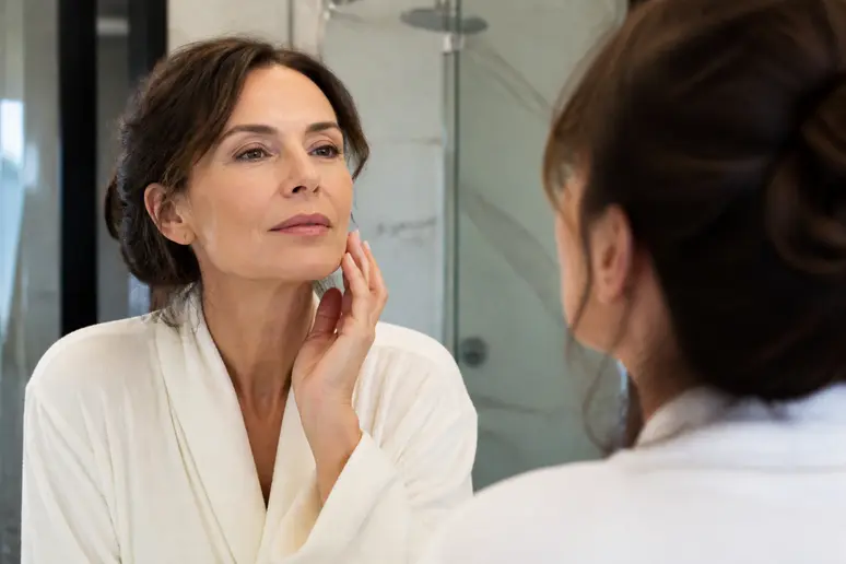 Femme parisienne miroir réfléchissant visage avant un potentiel smas-lifting pour rajeunissement.