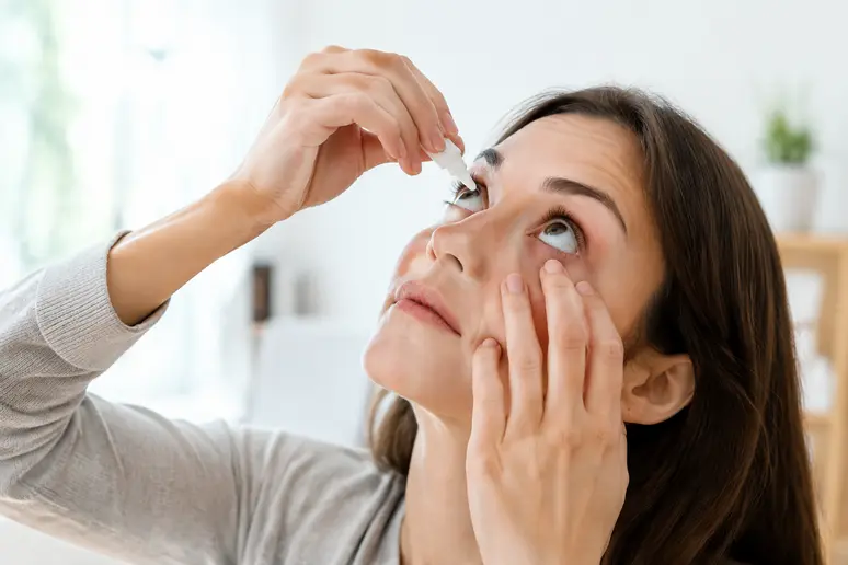 Patient appliquant des gouttes ophtalmiques pour soulager une sécheresse oculaire après une chirurgie oculoplastique